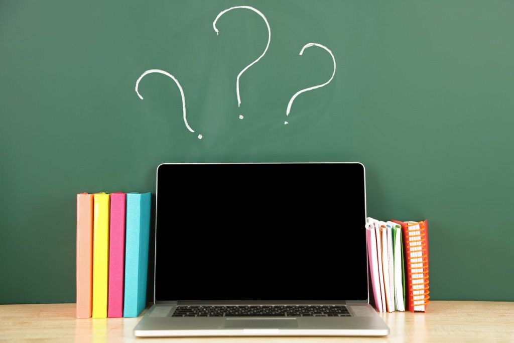 Laptop on table, on green blackboard background