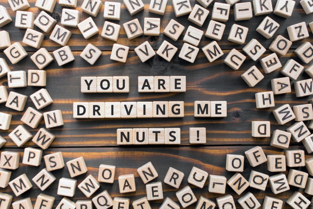 You are driving me nuts - phrase from wooden blocks with letters, to make someone very annoyed concept, random letters around, white background
