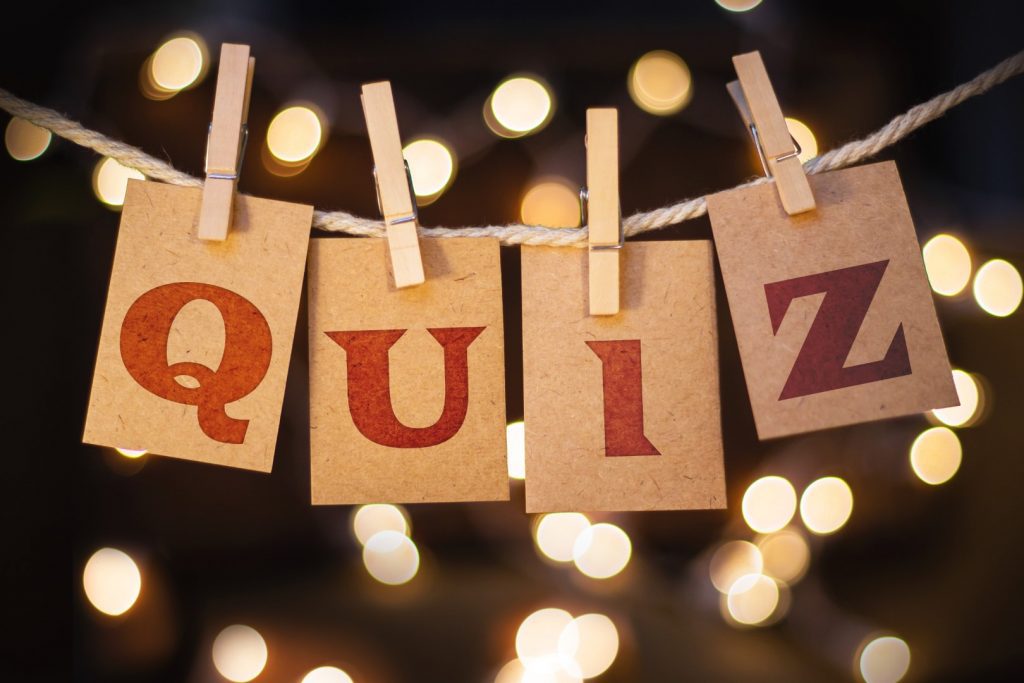 The word QUIZ printed on clothespin clipped cards in front of defocused glowing lights.